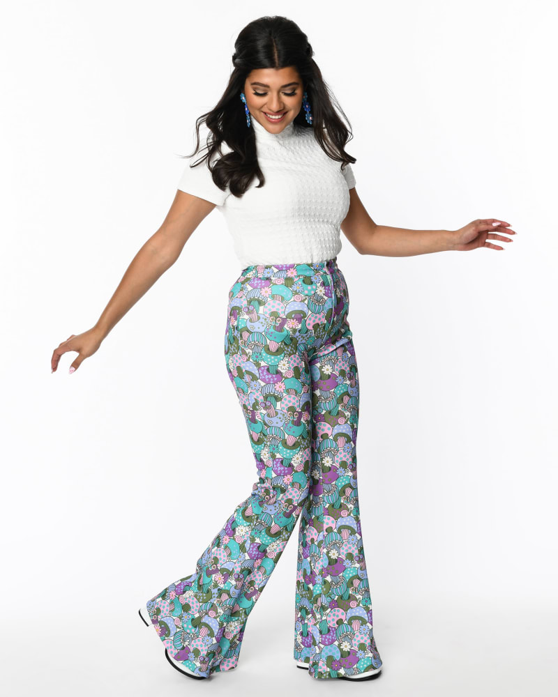 Front of a model wearing a size 1X Smak Parlour Teal Groovy Mushrooms Find Your Flare Pants in Teal, purple, green Mushroom print by Smak Parlour. | dia_product_style_image_id:329152